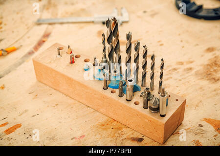 Close-up d'un grand ensemble d'exercices de métal pour une perceuse à main pour percer le bois sur une table en bois dans l'atelier Banque D'Images