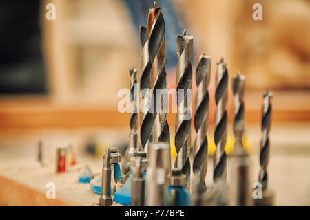 Close-up d'un grand ensemble d'exercices de métal pour une perceuse à main pour percer le bois sur une table en bois dans l'atelier Banque D'Images