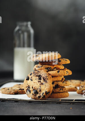Des biscuits fraîchement cuits sur rack de cookie avec du lait sur un fond sombre Banque D'Images