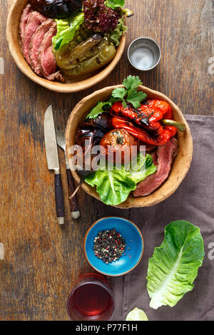 Le steak grillé et légumes grillés servis dans le pain sur la plaque de table en bois, vue du dessus Banque D'Images
