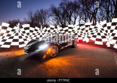 Corvette C7 noir sur l'affichage la nuit avec motif à damiers autour d'elle. Banque D'Images