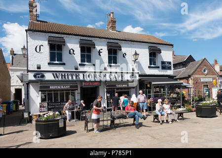 Les gens se détendre avec des glaces à l'extérieur du Cheval Blanc Café à Thirsk Marché dans le centre ville sur une chaude journée d'été Banque D'Images