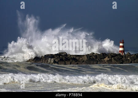 Tempête en mer dans une belle journée ensoleillée avec ciel bleu profond. Jetée et phare de Povoa de Varzim, Portugal port. Banque D'Images