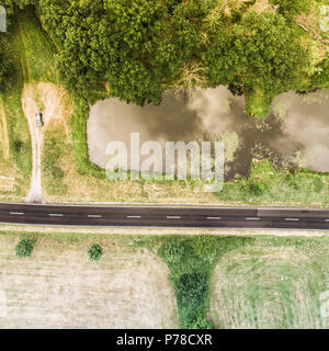 Vue aérienne d'un petit étang parallèle à une route de campagne dans la région de Saxe-anhalt avec des champs et des forêts dans la région environnante, faite avec drone Banque D'Images