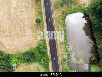 Vue aérienne d'un petit étang parallèle à une route de campagne dans la région de Saxe-anhalt avec des champs et des forêts dans la région environnante, faite avec drone Banque D'Images