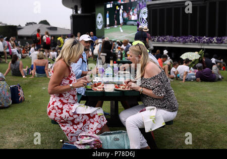 Spectateurs profiter de la nourriture à une table sur Murray Mound que la pluie cesse de jouer sur la troisième journée du tournoi de Wimbledon à l'All England Lawn Tennis et croquet Club, Wimbledon. Banque D'Images