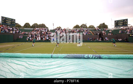 Le personnel au sol tirer la cour s'étend sur plus de trois que la pluie cesse de jouer sur la troisième journée du tournoi de Wimbledon à l'All England Lawn Tennis et croquet Club, Wimbledon. Banque D'Images