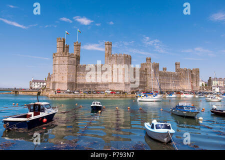 Château de Caernarfon au Pays de Galles, Royaume-Uni. Journée ensoleillée en été, avec des bateaux dans le port. Banque D'Images