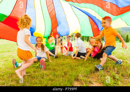 Happy kids se cachant sous le couvert de l'arc-en-ciel Banque D'Images