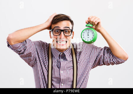 L'homme panique dans nerdy holding clock. Banque D'Images