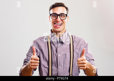 Nerdy man giving thumb up et sticking out tongue Banque D'Images