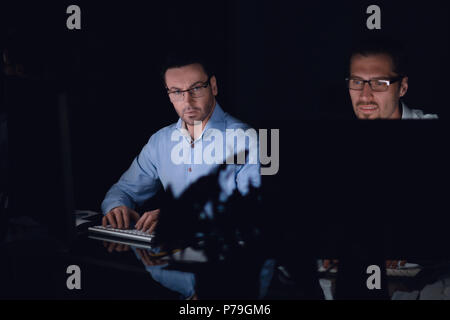 Close up.Les employés travaillent sur des ordinateurs dans un bureau sombre Banque D'Images