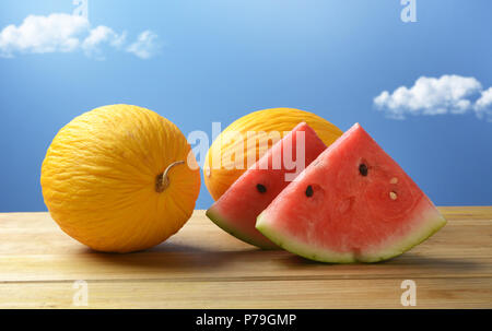 Melon jaune et rouge pastèque sur table en bois avec ciel bleu en arrière-plan - gros plan - fruits de Sicile Banque D'Images