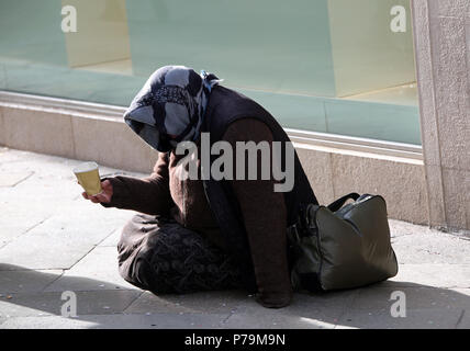 Personnes âgées gypsy demande l'aumône assis sur le sol avec un verre Banque D'Images