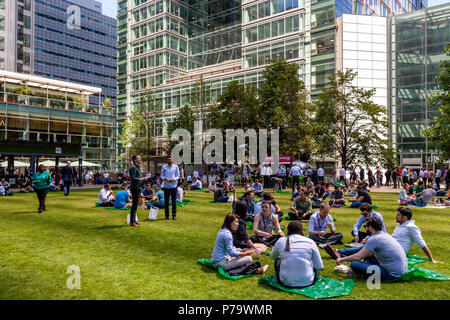 Les employés de bureau assis sur l'Herbe de manger le déjeuner, Canary Wharf, London, Royaume-Uni Banque D'Images