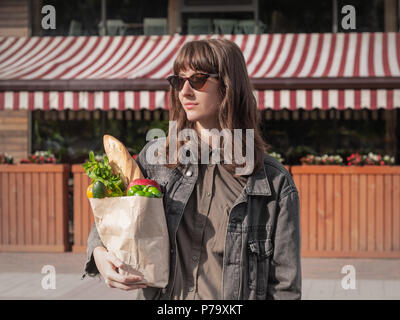 Attractive young woman in casual clothes holding style épicerie acheté de légumes locaux et d'une épicerie ou marché. Sac en Papier Recyclable de hea Banque D'Images