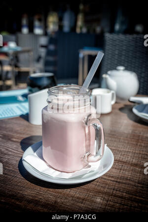 Strawberry milkshake boire dans un grand verre inhabituelle avec une poignée Banque D'Images