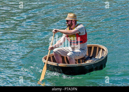 FESTIVAL DE PORTSOY ABERDEENSHIRE ECOSSE UN EXPERT DANS UN AVIRON CORACLE DANS LE PORT Banque D'Images