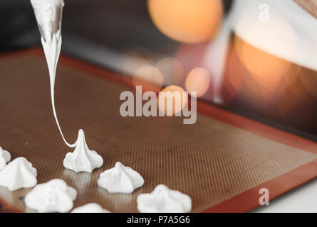 Cookies meringue pastel blanc cuisson avec poche à pâtisserie. Banque D'Images