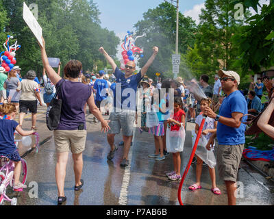 Oak Park, Illinois, USA 4 Juillet, 2018. Un hébergement sur la fête de l'indépendance défilé défilé refroidit les participants avec un spray d'eau de son arrosage dans cette banlieue à l'ouest de Chicago. Température ce 4 juillet ont été bien plus de 90 ºF/32ºC avec un indice de chaleur de plus de 100ºF. Credit : Todd Bannor/Alamy Live News Banque D'Images