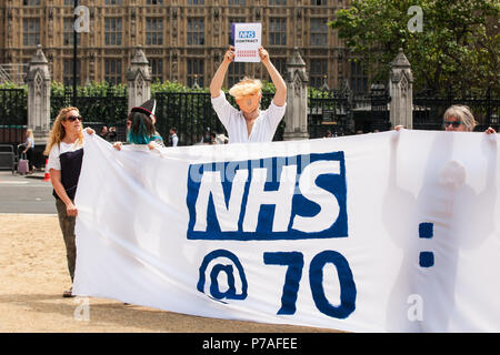 Londres, Royaume-Uni. 5 juillet, 2018. Des militants de Docs pas Flics et l'équipe de tenir une Anti-Swindle NHS banner reading 'NHS@70 : pas de frontières dans le domaine de la santé' dans la place du Parlement sur le 70e anniversaire du Service national de santé. Docs pas Cops est un groupe composé de médecins, infirmiers, militants du VIH, les élèves, les enseignants et les laïcs qui croient que les soins de santé sont un droit de l'homme et s'opposent aux politiques du gouvernement qui pourrait faire à n'importe qui peur consulter un médecin pour des raisons de coût ou de statut d'immigration. Credit : Mark Kerrison/Alamy Live News Banque D'Images