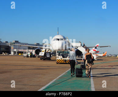 Deux femmes à pied vers un Thomas Cook airlines Airbus 321 bagages à main tirant derrière eux. Banque D'Images