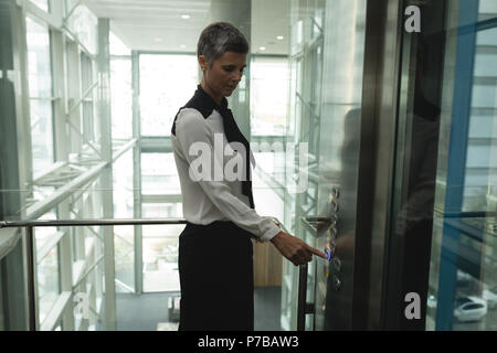 Businesswoman en appuyant sur un bouton dans l'ascenseur Banque D'Images