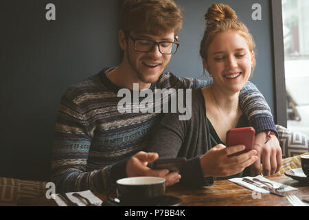 Couple à l'aide de leurs téléphones portables au restaurant Banque D'Images