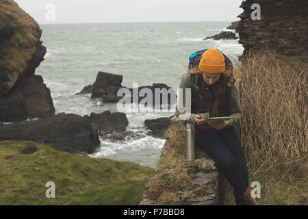 Female hiker reading a map et en consommant de l'alcool Banque D'Images