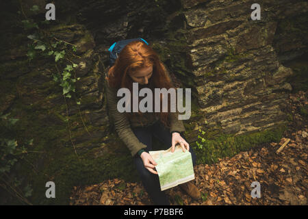 Female hiker with backpack lecture d'une carte dans la forêt Banque D'Images