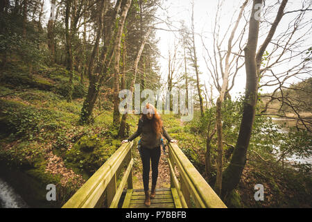 Female hiker marcher sur le pont dans la forêt Banque D'Images