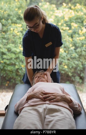 Physiothérapeute donnant un massage de la tête à senior woman Banque D'Images