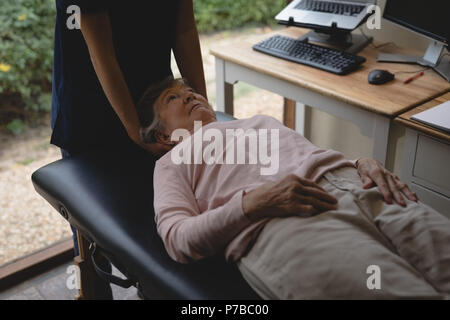 Physiothérapeute donnant un massage de la tête à senior woman Banque D'Images