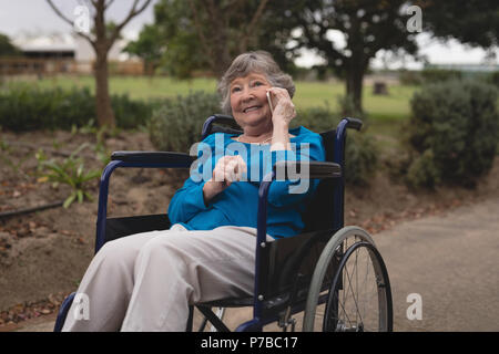 Senior woman on wheel chair talking on a mobile phone Banque D'Images