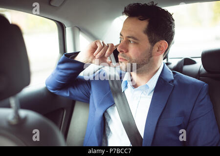 Businessman talking on mobile phone in a car Banque D'Images