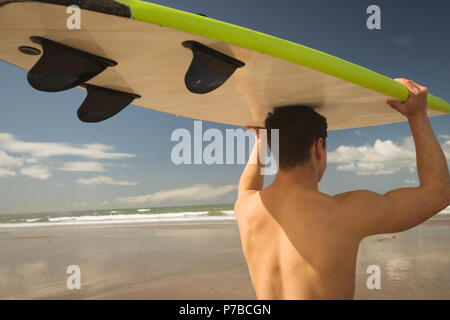 Surfer carrying surfboard sur sa tête le Banque D'Images