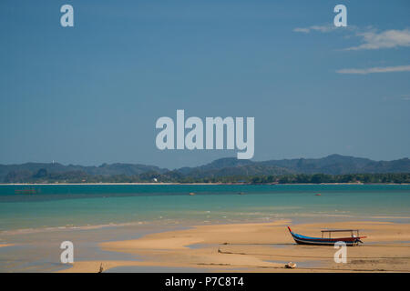 Une belle scène d'un toit en bois bateau amarré sur une plage de sable fin à marée basse, entourée par le bleu turquoise de l'eau avec une plage et une... Banque D'Images