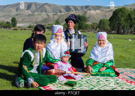 La famille kazakhe en vêtements traditionnels, à l'écoute de joueur d'accordéon, pour un usage éditorial uniquement, le sati village, Tian Shan, Kazakhstan Banque D'Images