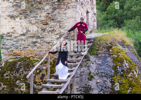 Couple en costume traditionnel géorgien en ordre décroissant des escaliers de la tour de l'amour, pour un usage éditorial uniquement, Ushguli, région de Svaneti, Géorgie Banque D'Images