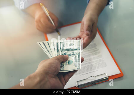 Man lot de centaines de dollars. Close up of business man signature contrat à conclure une entente, les modalités du contrat. Banque D'Images