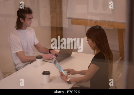 Des collègues à l'aide d'ordinateur portable et tablette numérique Banque D'Images