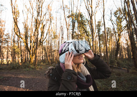 Femme à l'aide de casque de réalité virtuelle dans la forêt Banque D'Images