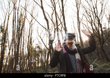 Femme à l'aide de casque de réalité virtuelle dans la forêt Banque D'Images