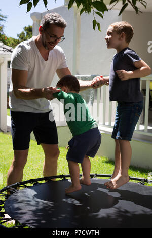 Père jouant avec ses fils dans le jardin Banque D'Images