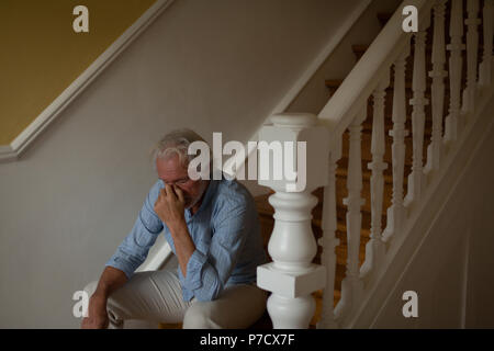 Senior man sitting on stairs at home Banque D'Images