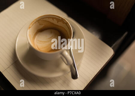 Tasse de café vide avec soucoupe et cuillère sur journal Banque D'Images
