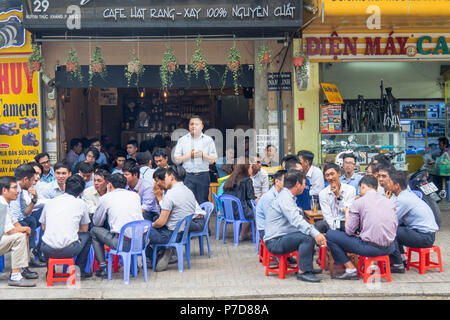 Travail de bureau assis sur des tabourets en plastique et des chaises en train de dîner al fresco sur le trottoir à Ho Chi Minh City, Vietnam. Banque D'Images