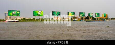 Barge de transport en vrac Transport d'une charge et d'un traversier sur la rivière Saigon, avec l'emblématique des panneaux d'Heineken dans l'arrière-plan., Ho Chi Minh City, Vietnam. Banque D'Images