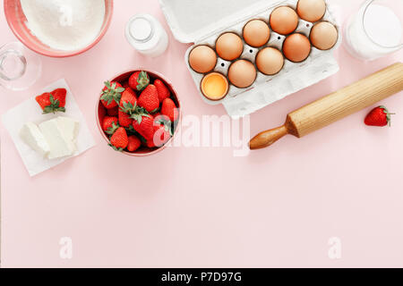 Ingrédients de base pour faire de tarte aux fraises ou gâteau sur fond rose (oeufs, farine, lait, sucre, fraise) avec copie espace haut, vue, télévision lay. Baker Banque D'Images