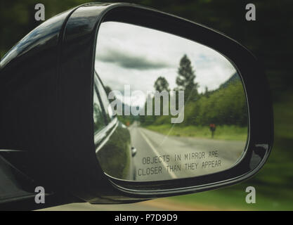 Close-up d'un rétroviseur avec les objets texte en miroir sont plus proches qu'ils apparaissent. Voiture sur la route. Banque D'Images